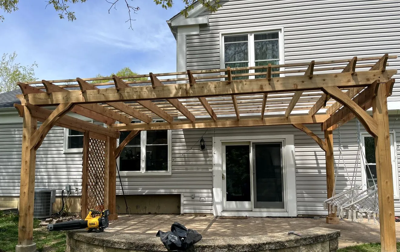 Pergola over a paver patio with stone seating wall and hanging chair