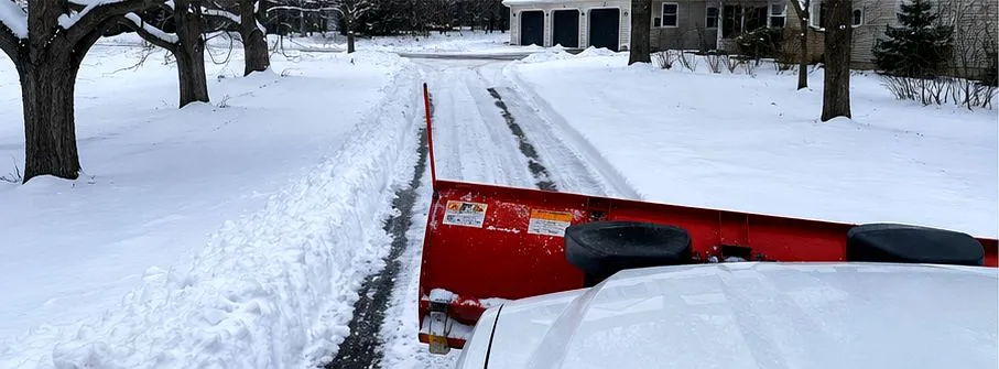Truck plow clearing a snowy driveway